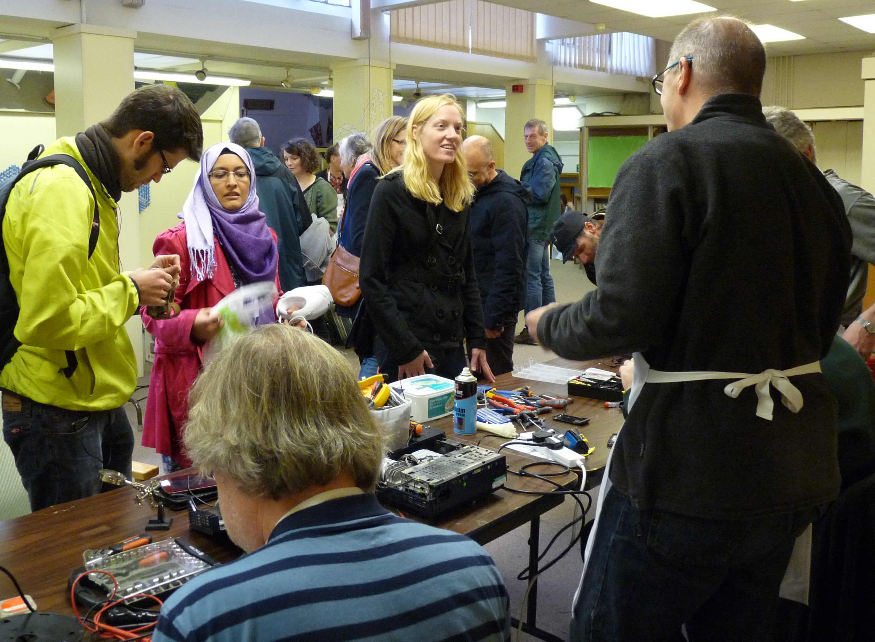 Neighbors gather around tools and opened electronics at Reading Repair Cafe in England in November 2015
